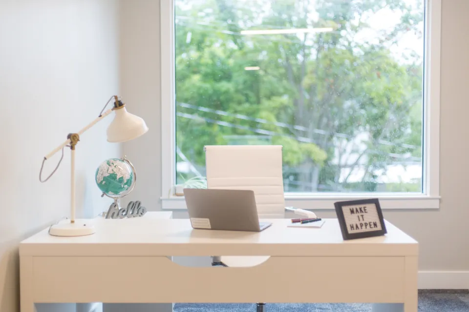 Bright home office desk with a laptop by a window
